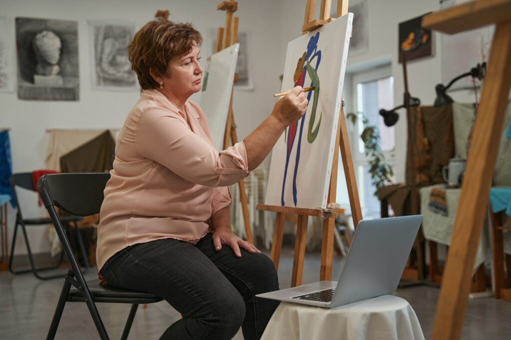Attente vrouw op leeftijd brengt weekend door in kunstatelier kunstzinnige therapie