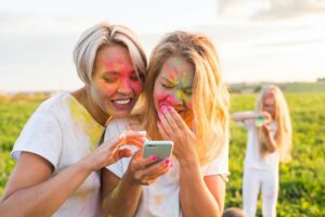 Indian festival of holi, people concept - Two laughing girls with colourful powder on the faces look